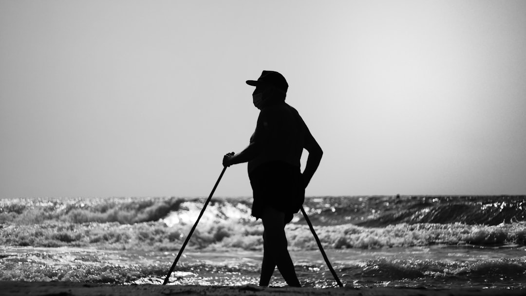 silhouette of man holding stick standing on beach