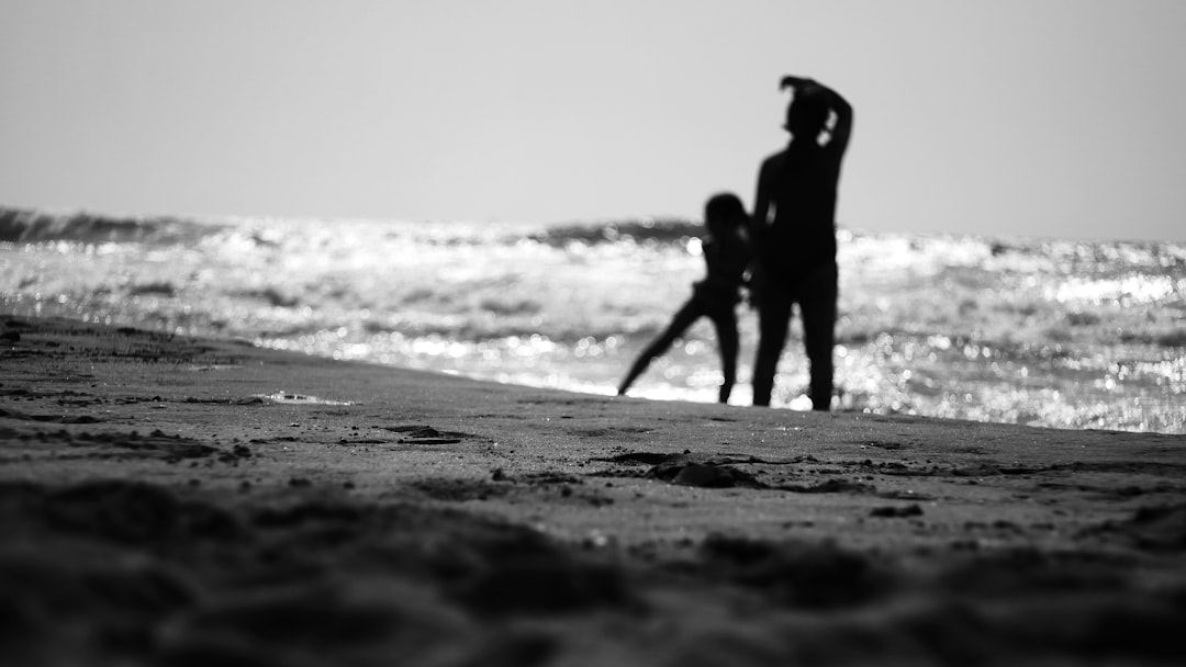 grayscale photo of 2 women walking on beach