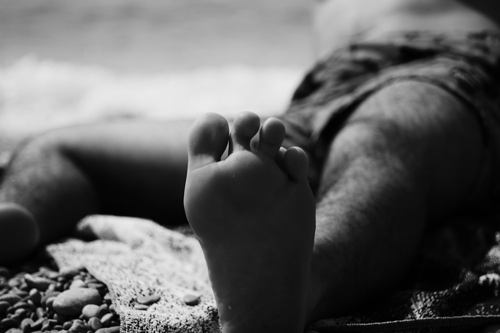 grayscale photo of persons feet on beach