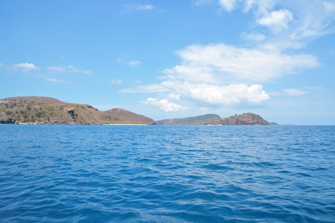 blue sea near brown mountain under blue sky during daytime