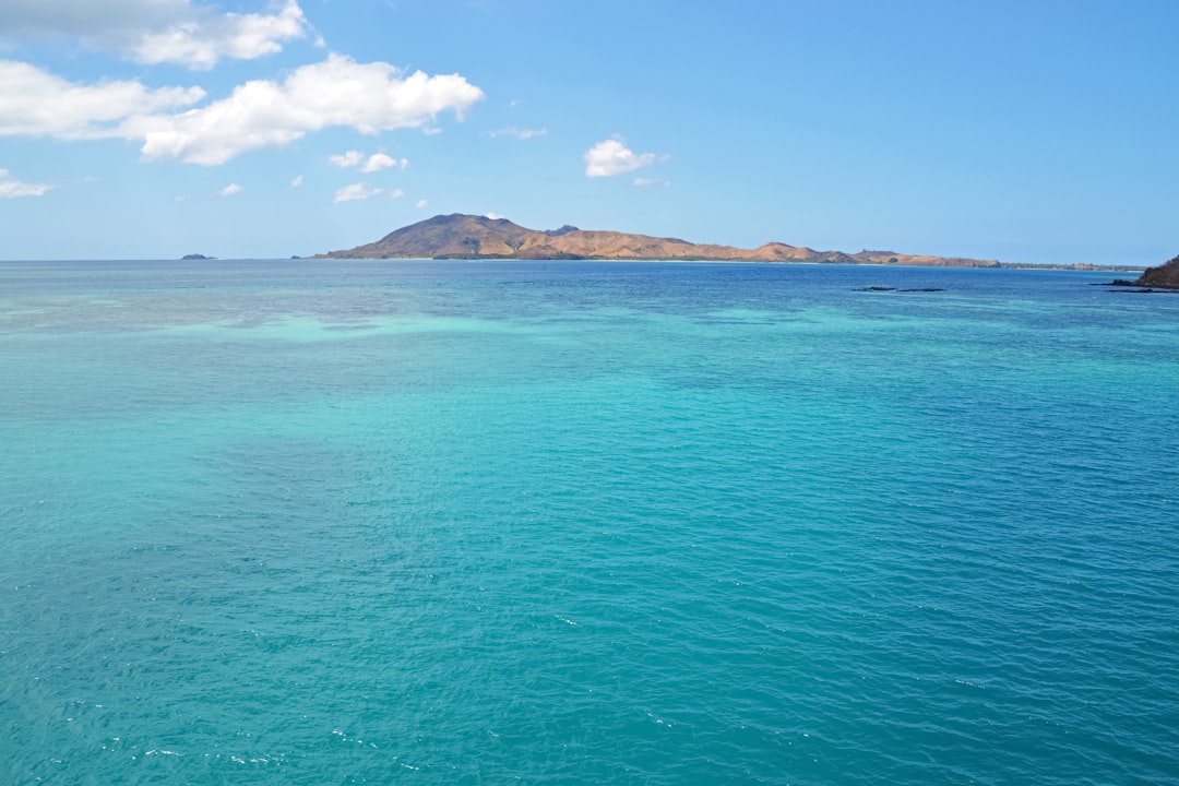 green and brown island on blue sea under blue sky during daytime