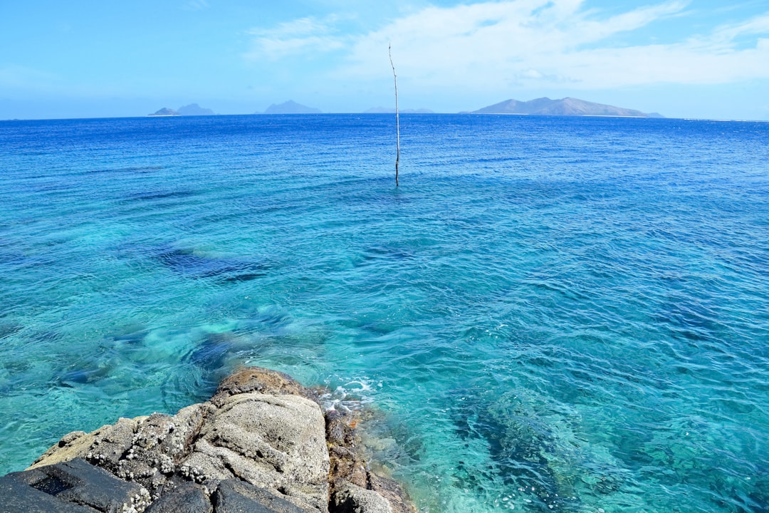 brown rock formation on sea under blue sky during daytime