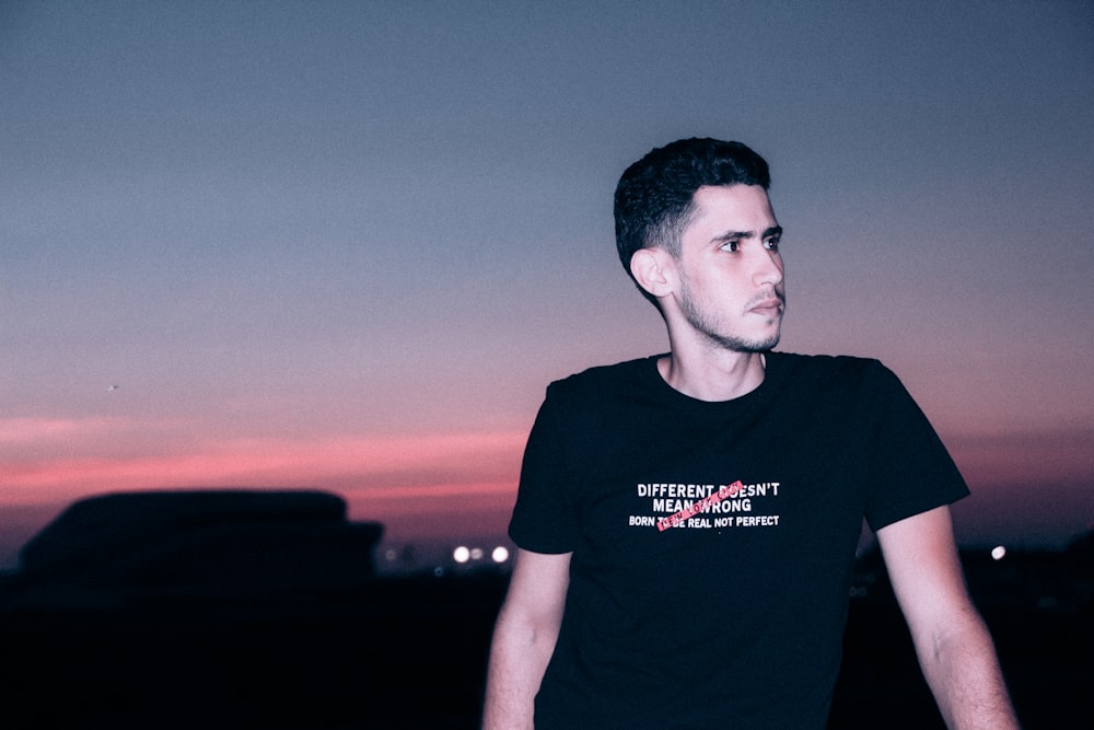 man in black crew neck t-shirt standing during sunset