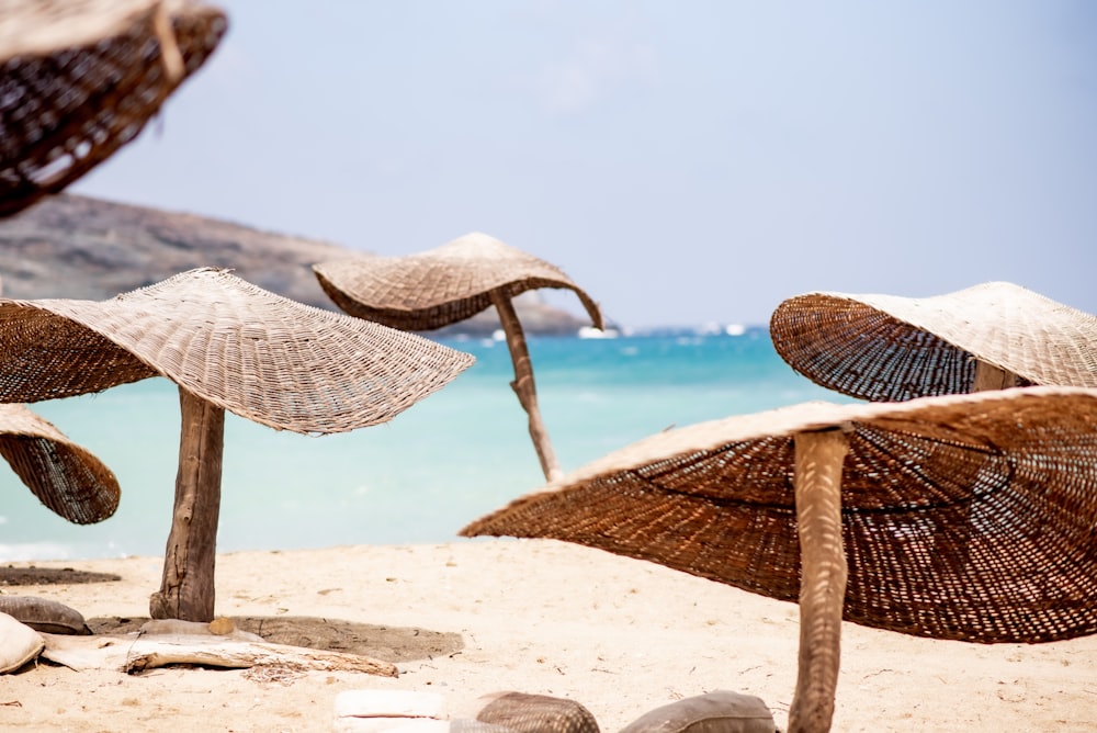 낮 동안 수역 근처의 하얀 모래 위에 갈색 고리 버들 세공 의자