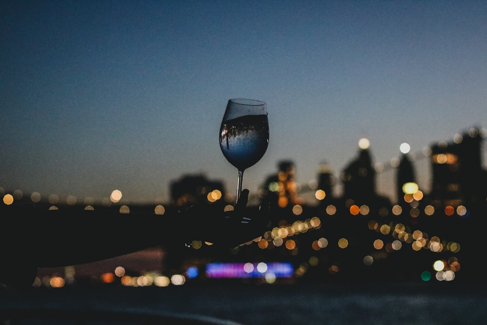 clear wine glass with brown liquid during night time