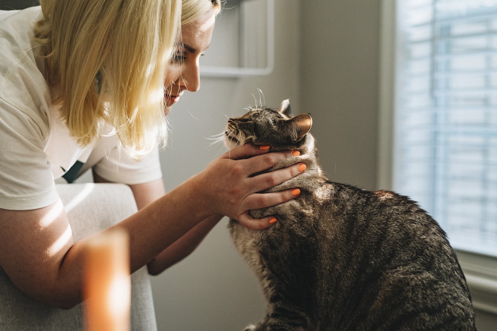 茶色のぶち猫を抱く白いシャツの女性