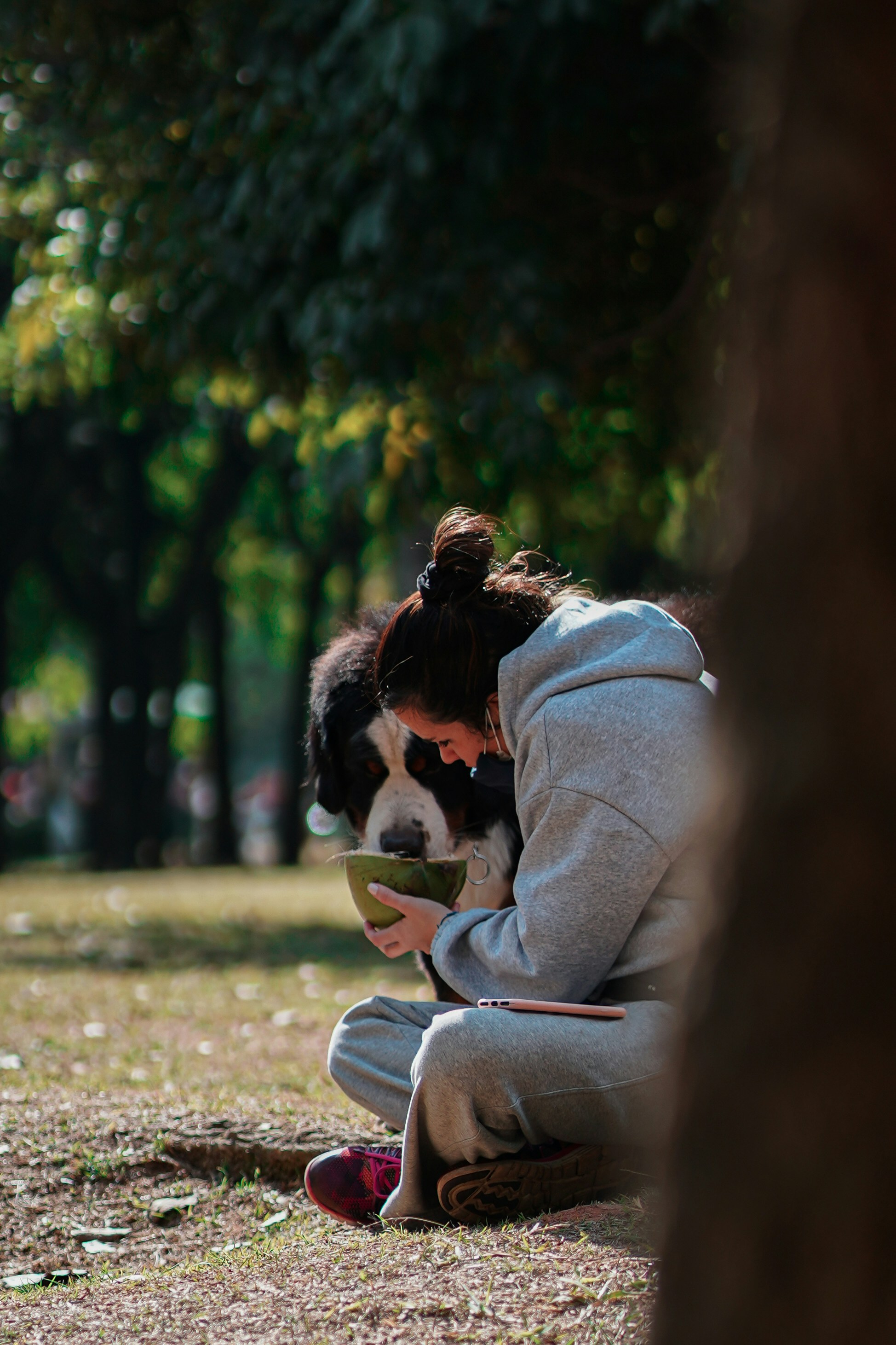 woman in gray hoodie sitting on green grass field during daytime