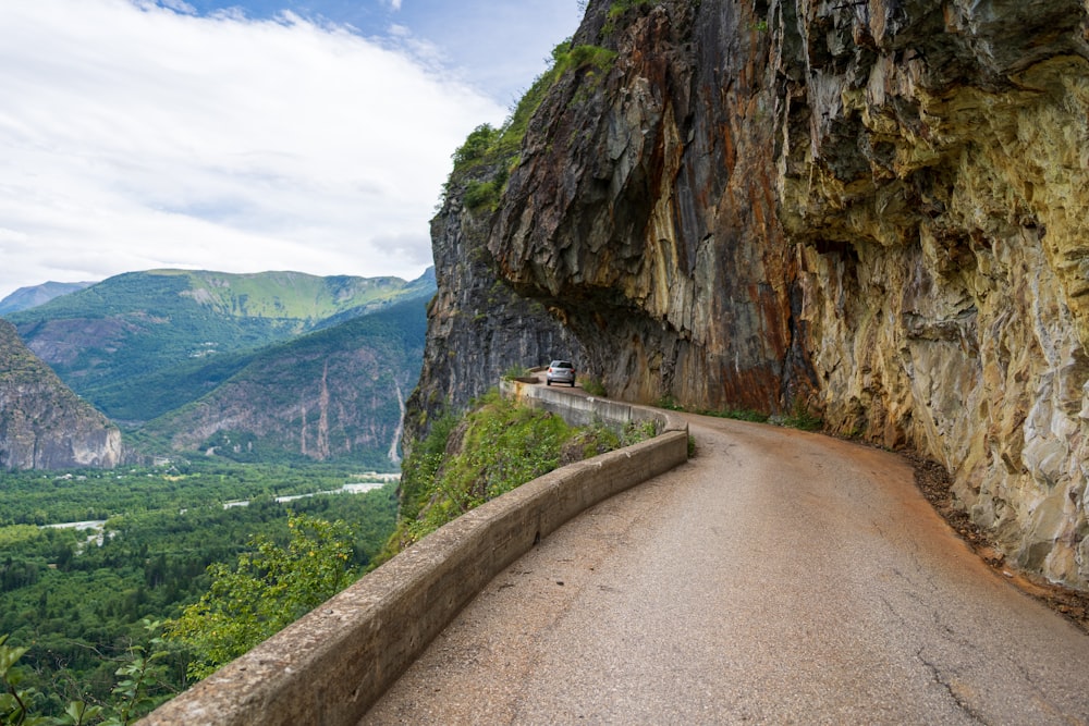 gray concrete road between brown rocky mountains during daytime