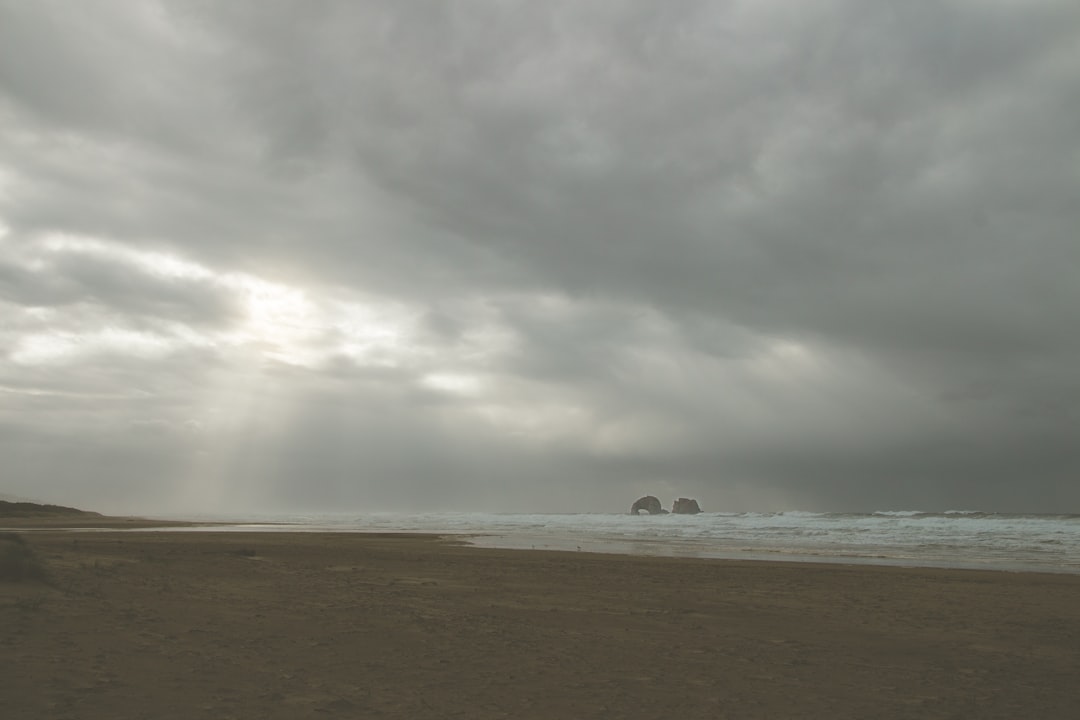 sea waves crashing on shore under cloudy sky