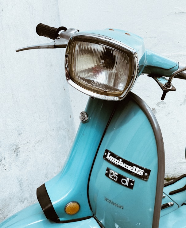 blue and silver motorcycle beside white wall