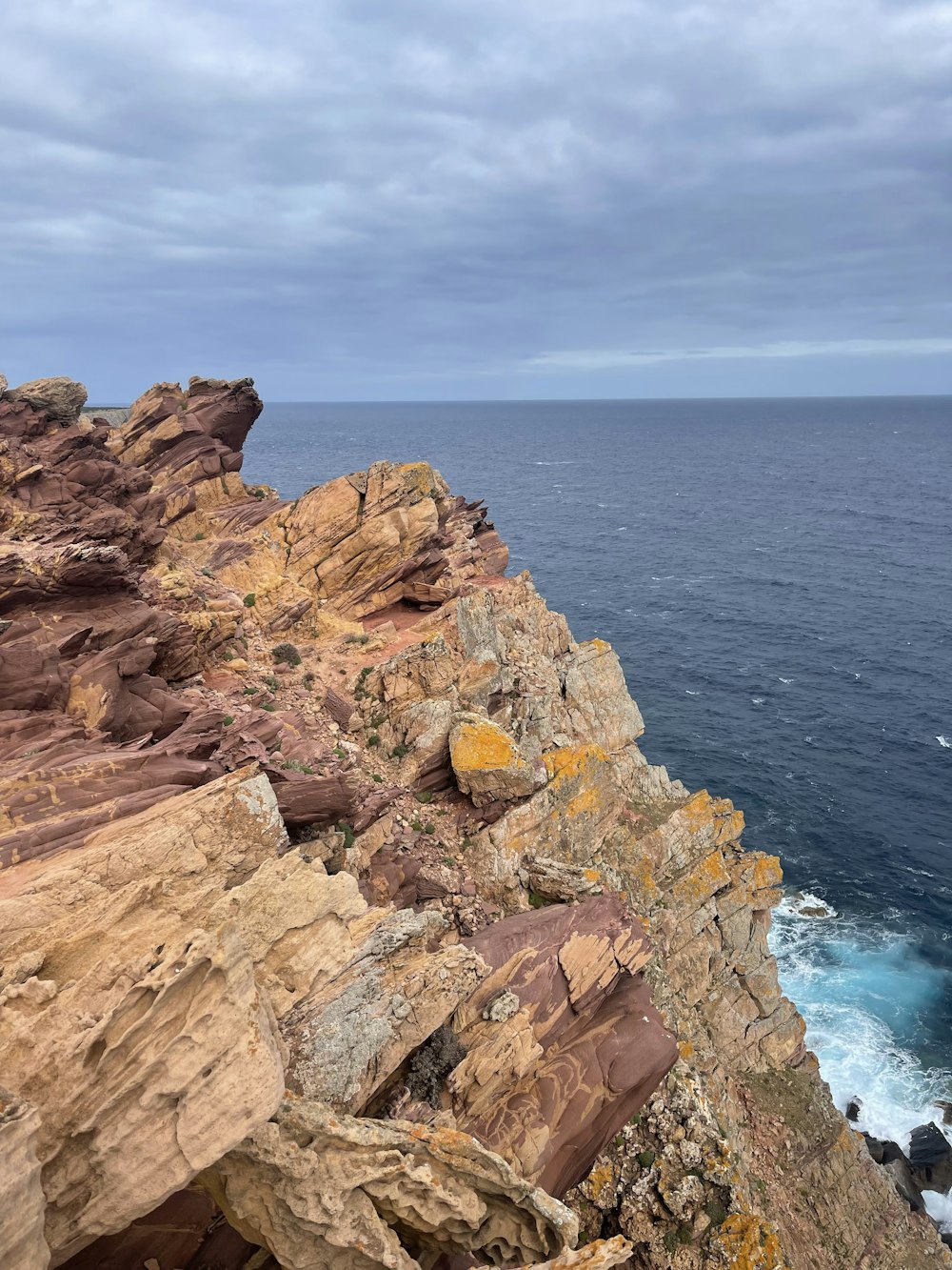 braune Felsformation am blauen Meer unter weißen Wolken tagsüber