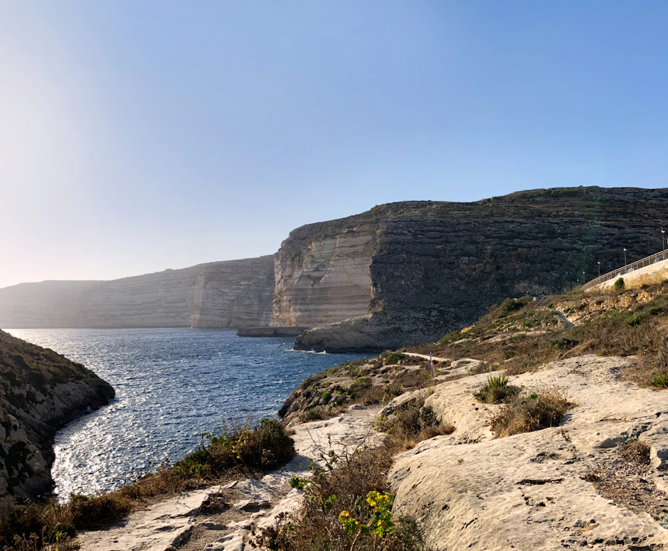 Rocky cliff face with lush vegetation rises from the ocean's surface in scenic landscape