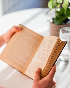 person reading book on table