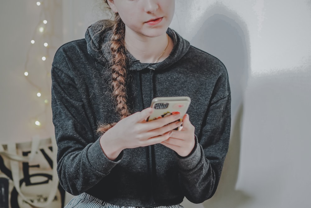 woman in black sweater holding white smartphone