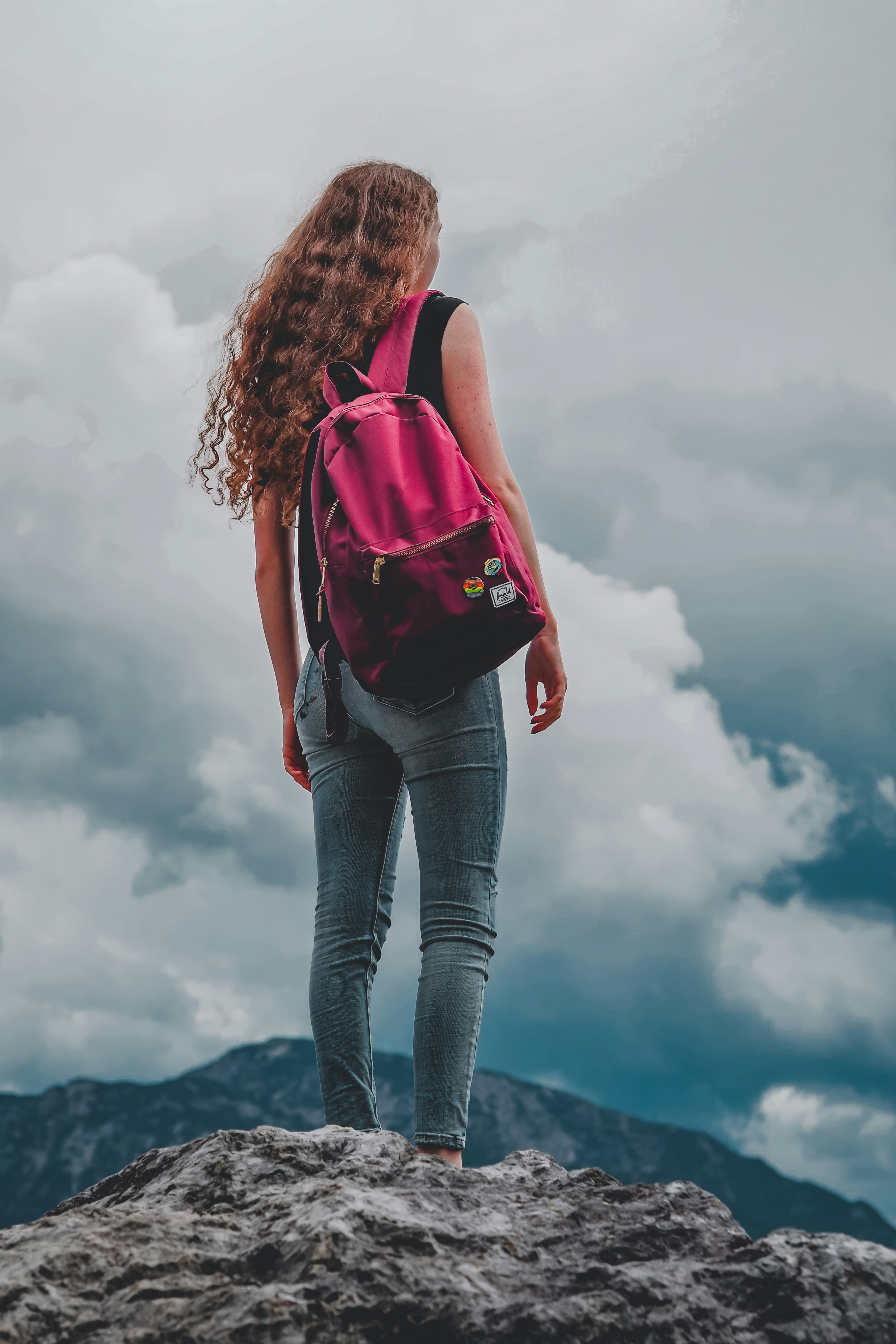 woman in red tank top and blue denim jeans with black and red backpack