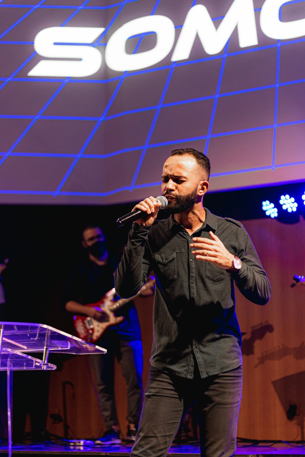 man in black suit singing on stage