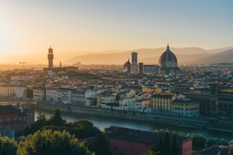 A serene sunset view over the terracotta rooftops of Florence with the Duomo softly glowing in the distance.