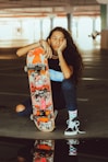 woman in blue tank top holding orange and black skateboard