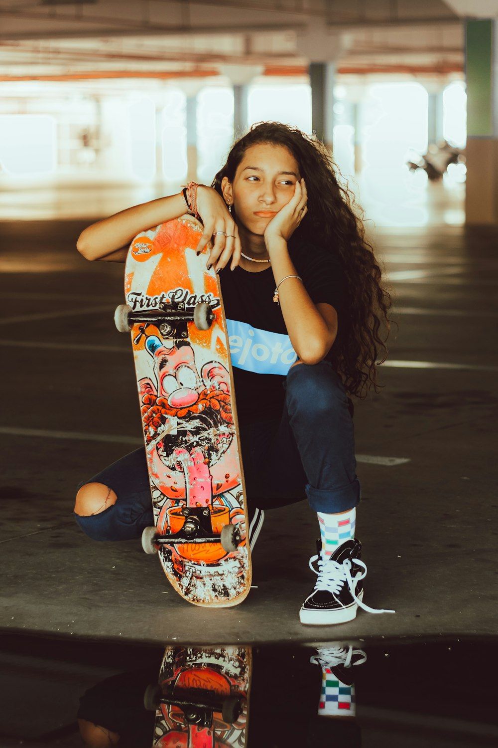 woman in blue tank top holding orange and black skateboard