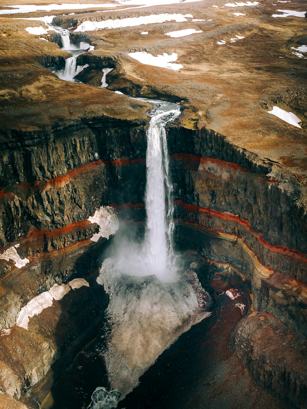 water falls on brown rocky mountain during daytime