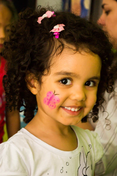 girl in white crew neck shirt with pink and white polka dots on her face