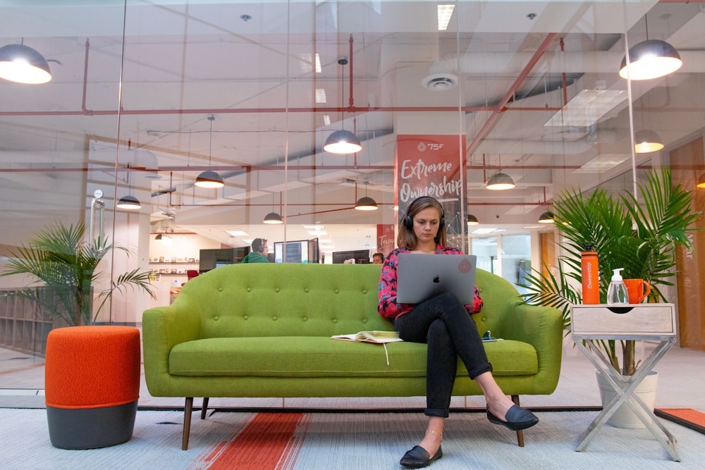 woman in pink long sleeve shirt and black pants sitting on green couch