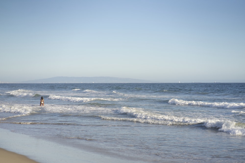 person in red shirt walking on beach during daytime