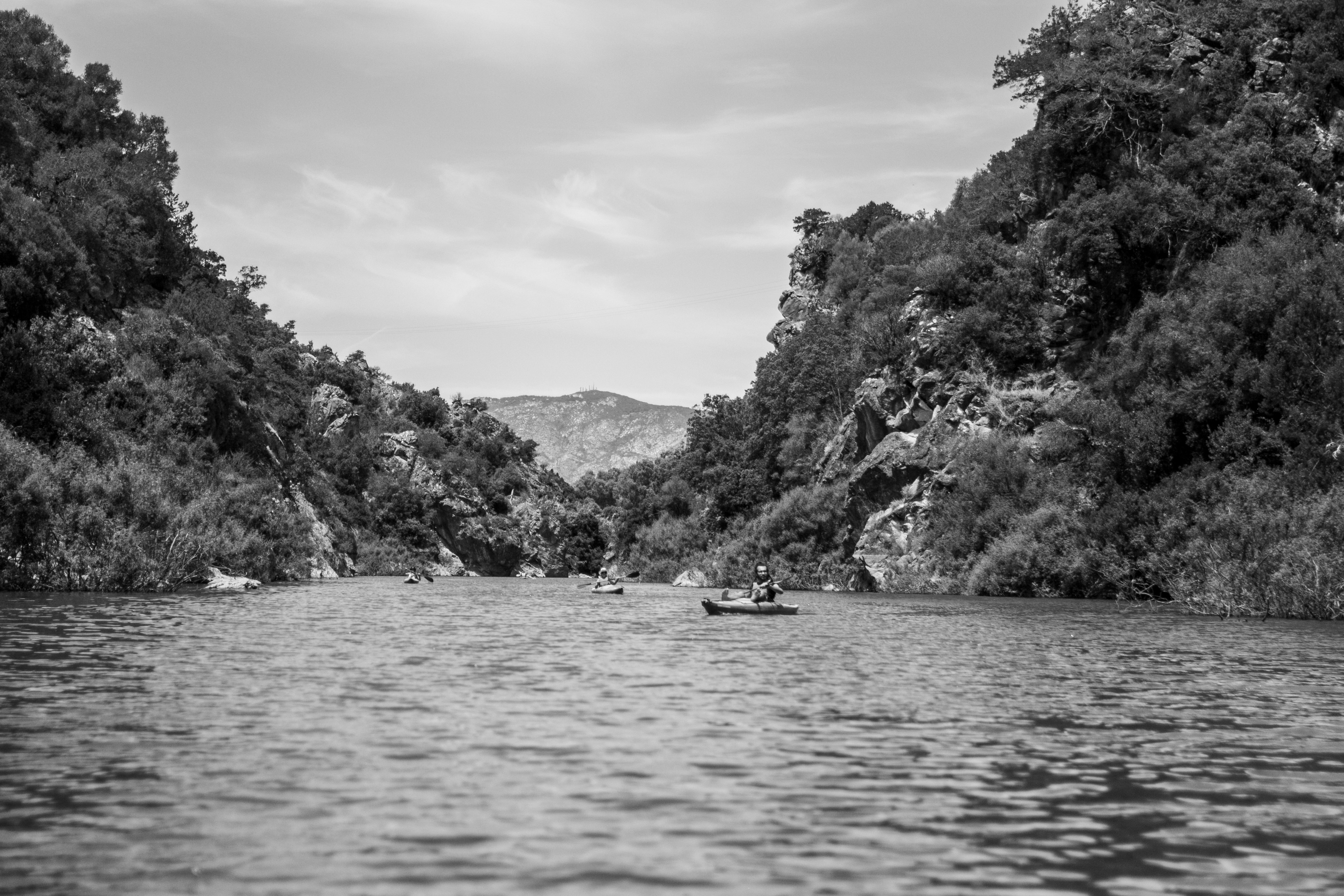 Grayscale photo of boat on body of water near mountain