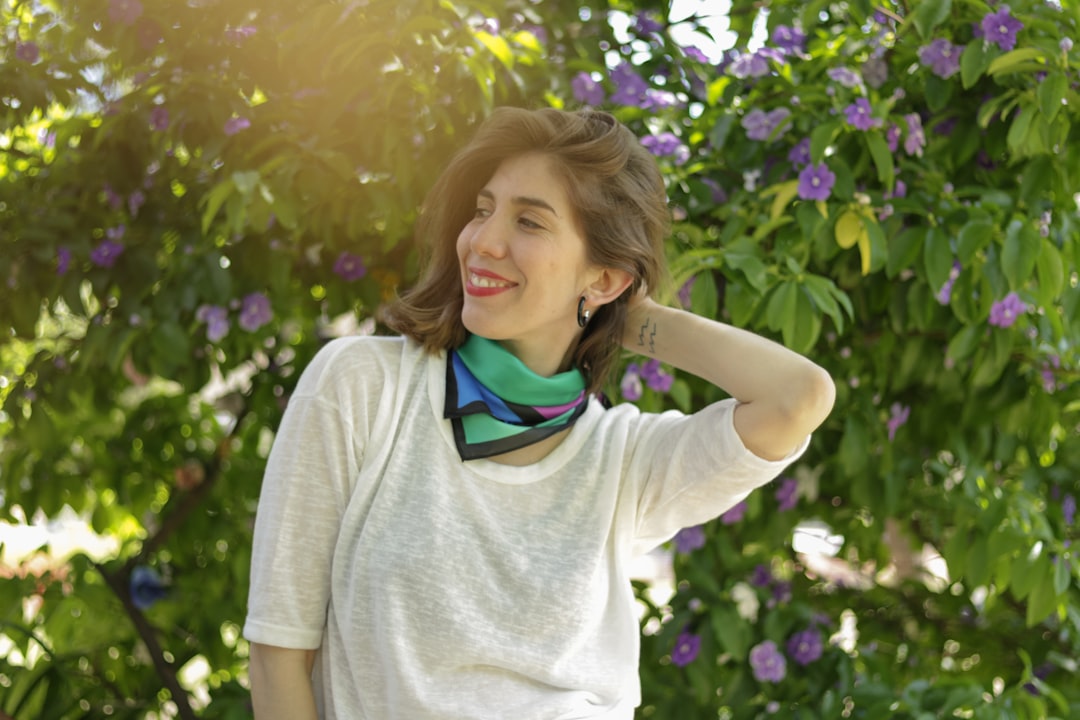 woman in gray long sleeve shirt standing near purple flowers