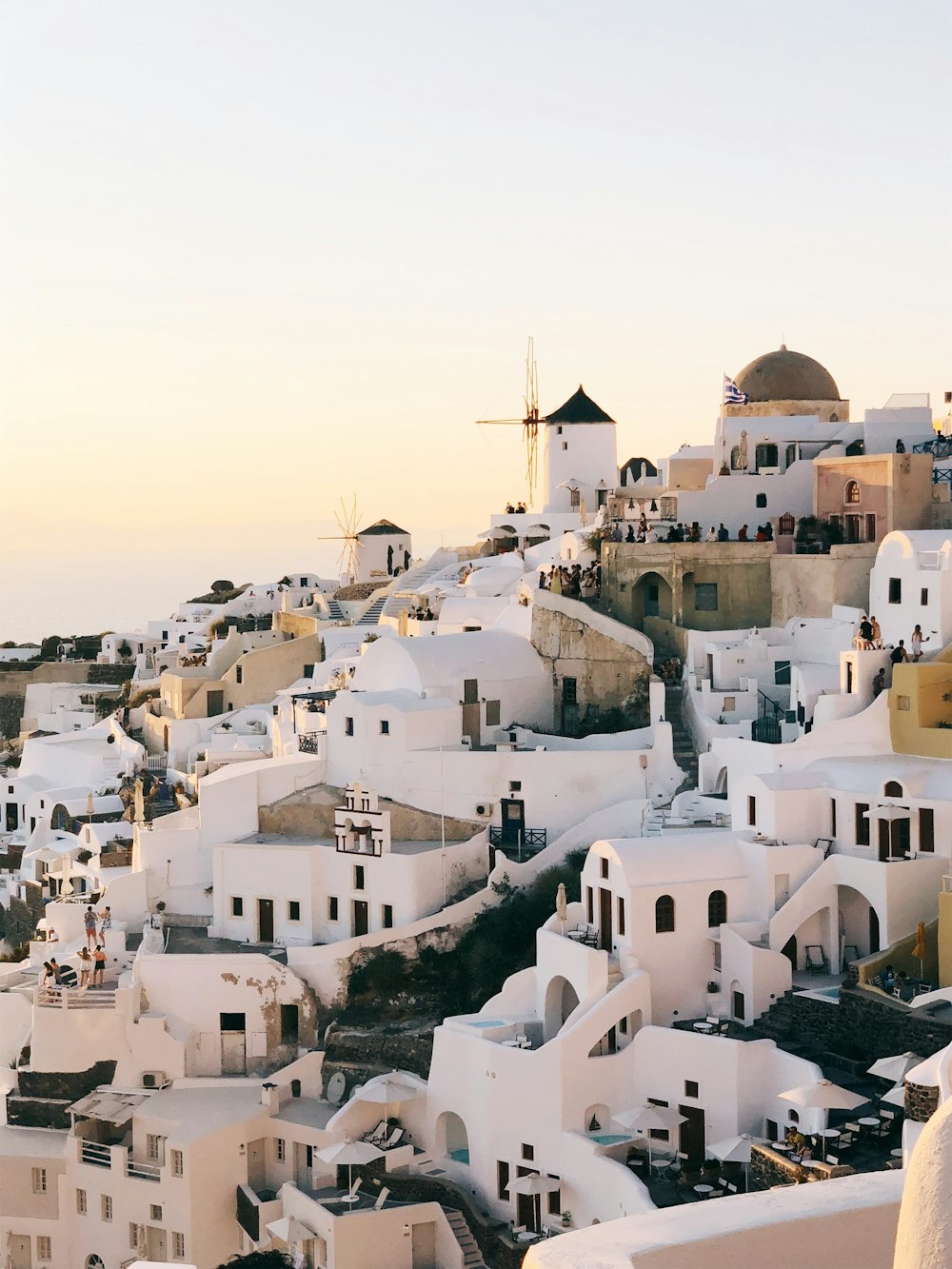 a view of a hillside with white buildings and windmills