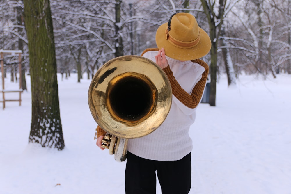 person in white long sleeve shirt and black pants holding brass trumpet