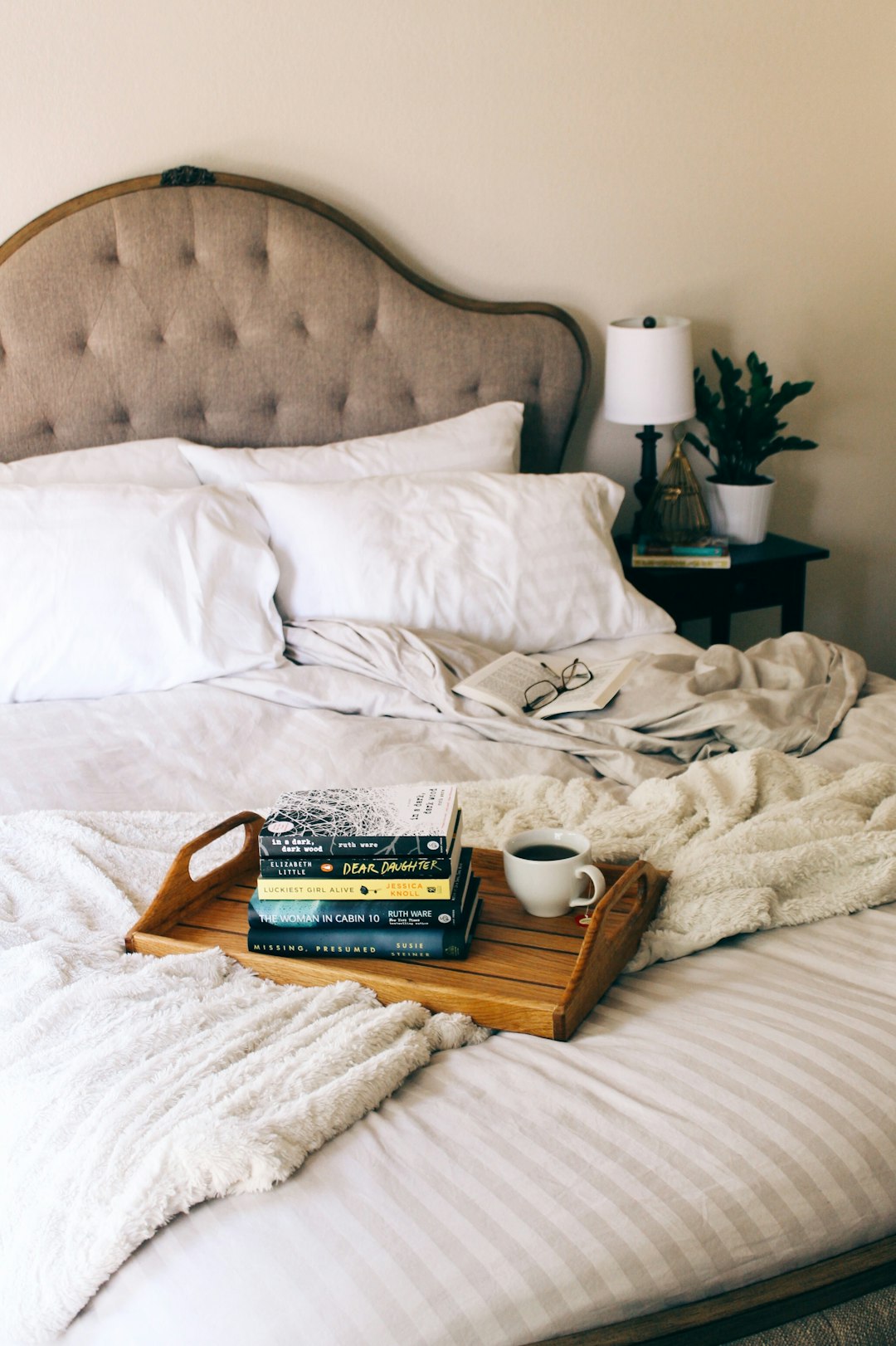 white bed linen with brown wooden table and books