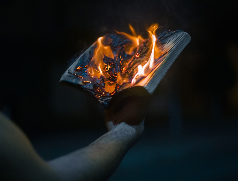 person holding burning paper during nighttime