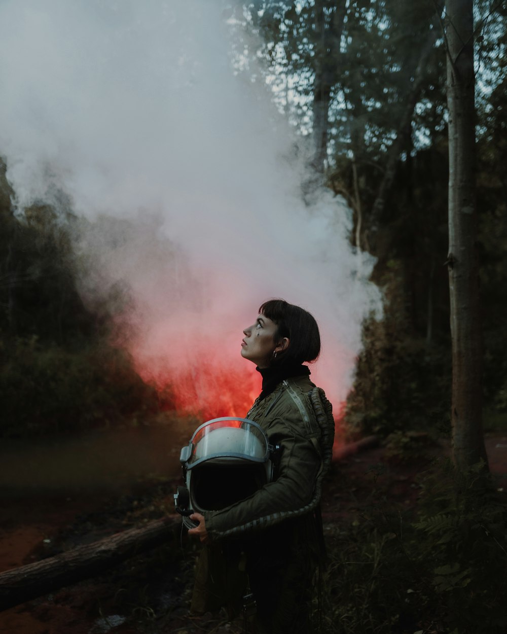 man in black jacket and black backpack standing on road with smoke