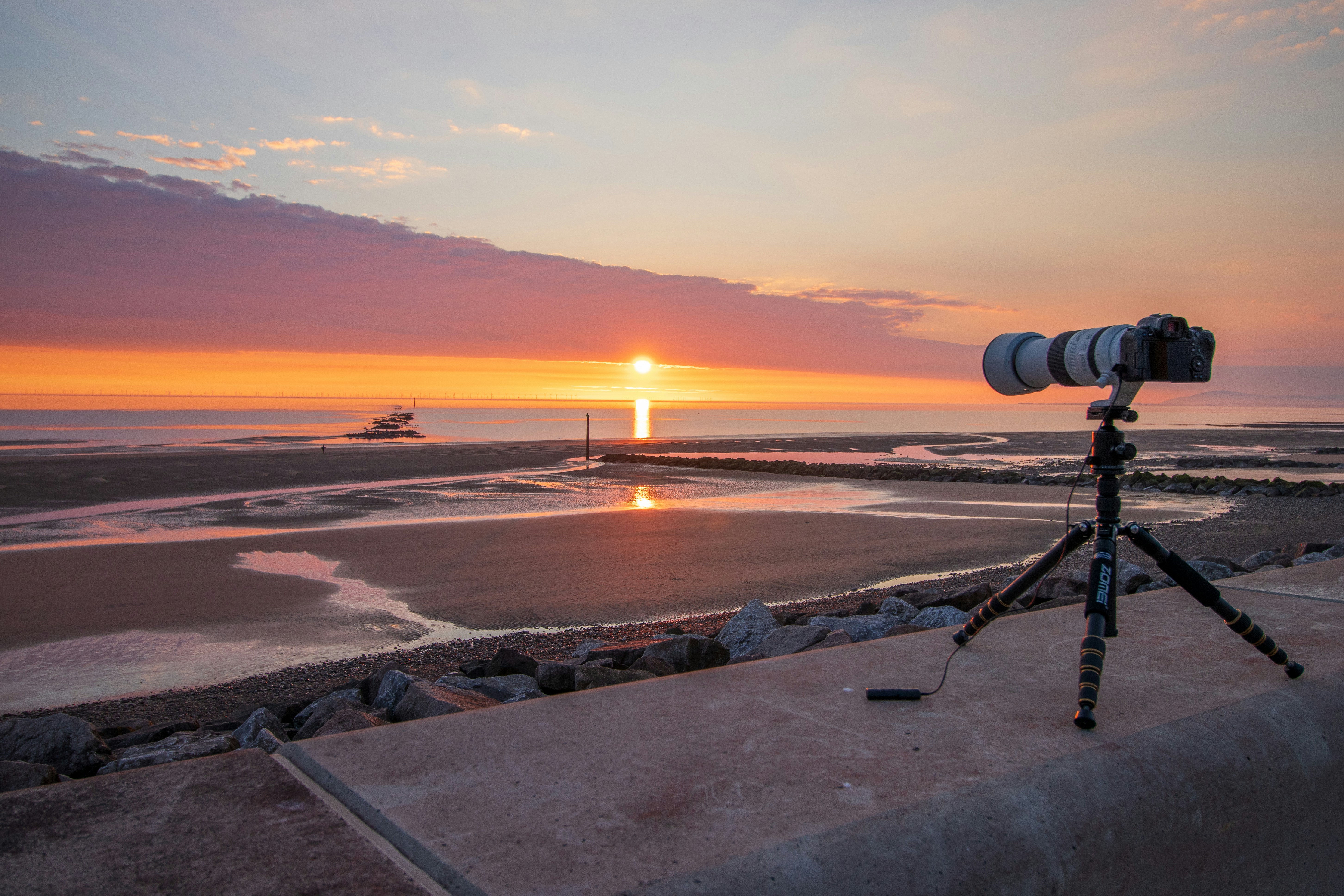 Professional camera on a tripod overlooking the sea at sunset.