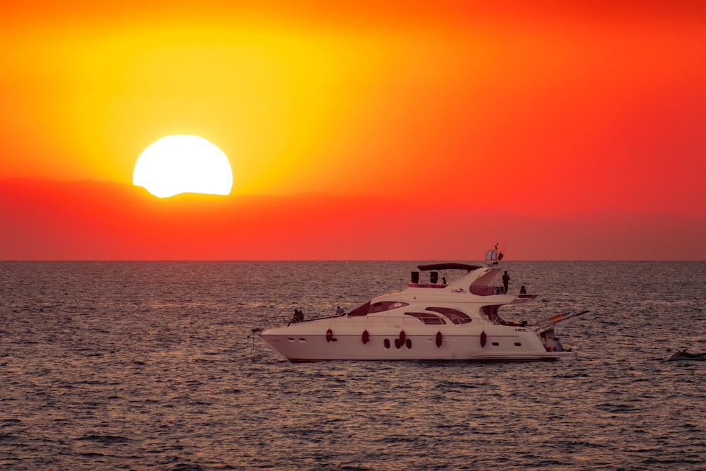 white yacht on sea during sunset