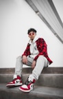 man in red and white jacket sitting on concrete stairs