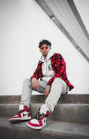 Casual streetwear look with a cropped jacket, high-waisted pants, and chunky sneakers on city steps.