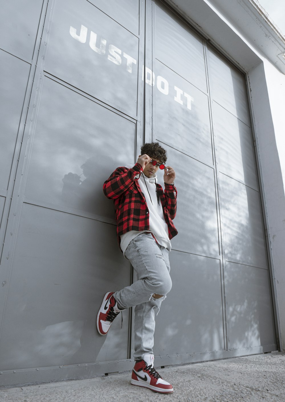 man in red jacket and gray pants sitting on gray wall