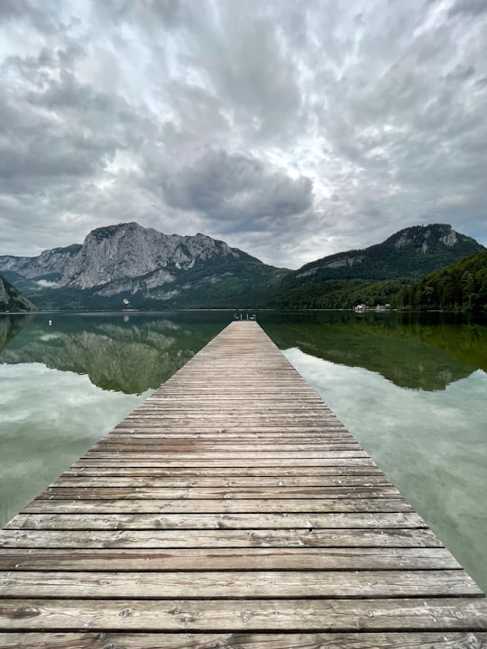 brown wooden dock on lake near mountain under cloudy sky during daytime in Ruine Pflindsberg Austria