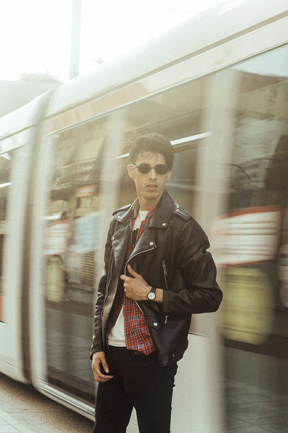 man in black leather jacket standing beside train