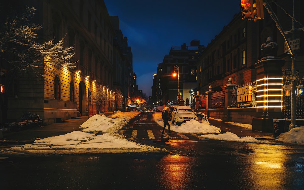 snow covered road between buildings during night time