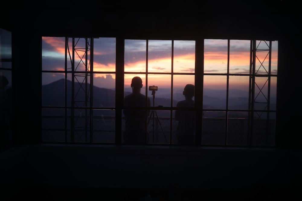 silhouette of people standing on window during sunset