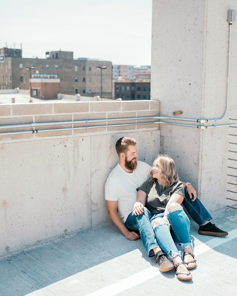 uomo e donna che si siedono sul muro di cemento durante il giorno