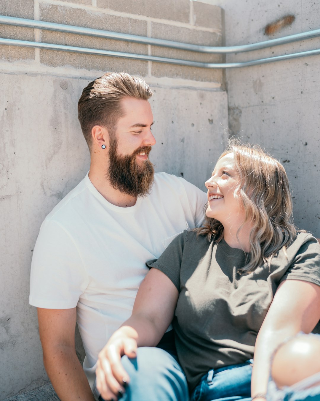 man in white crew neck t-shirt sitting beside woman in gray and black dress