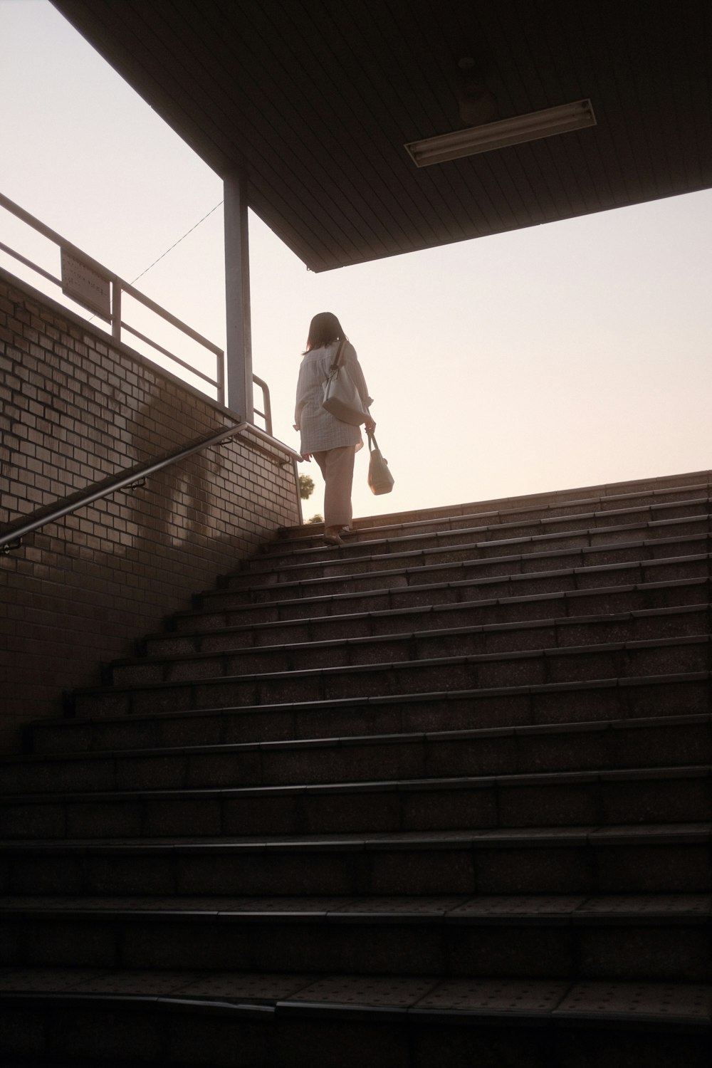 man in white long sleeve shirt and white pants walking down the stairs