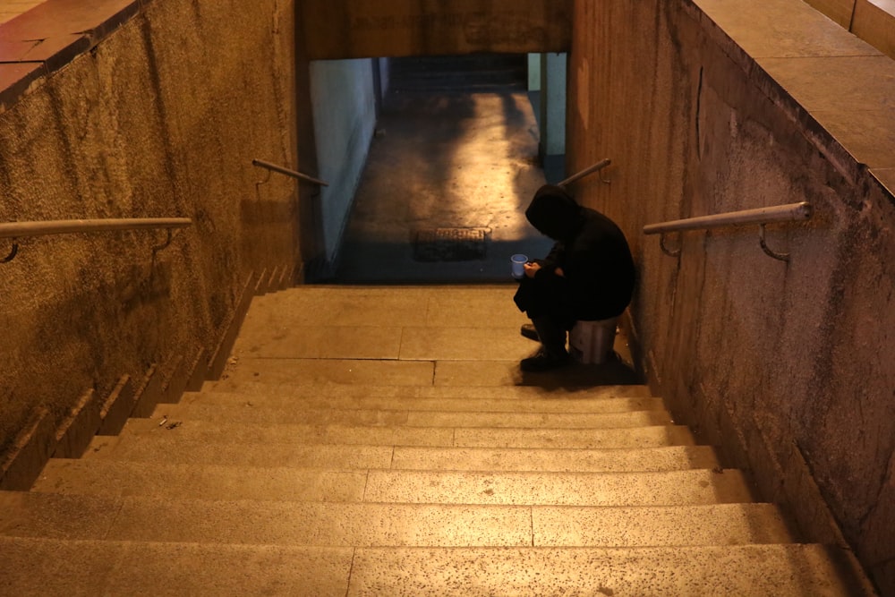 uomo in giacca nera che si siede sulle scale