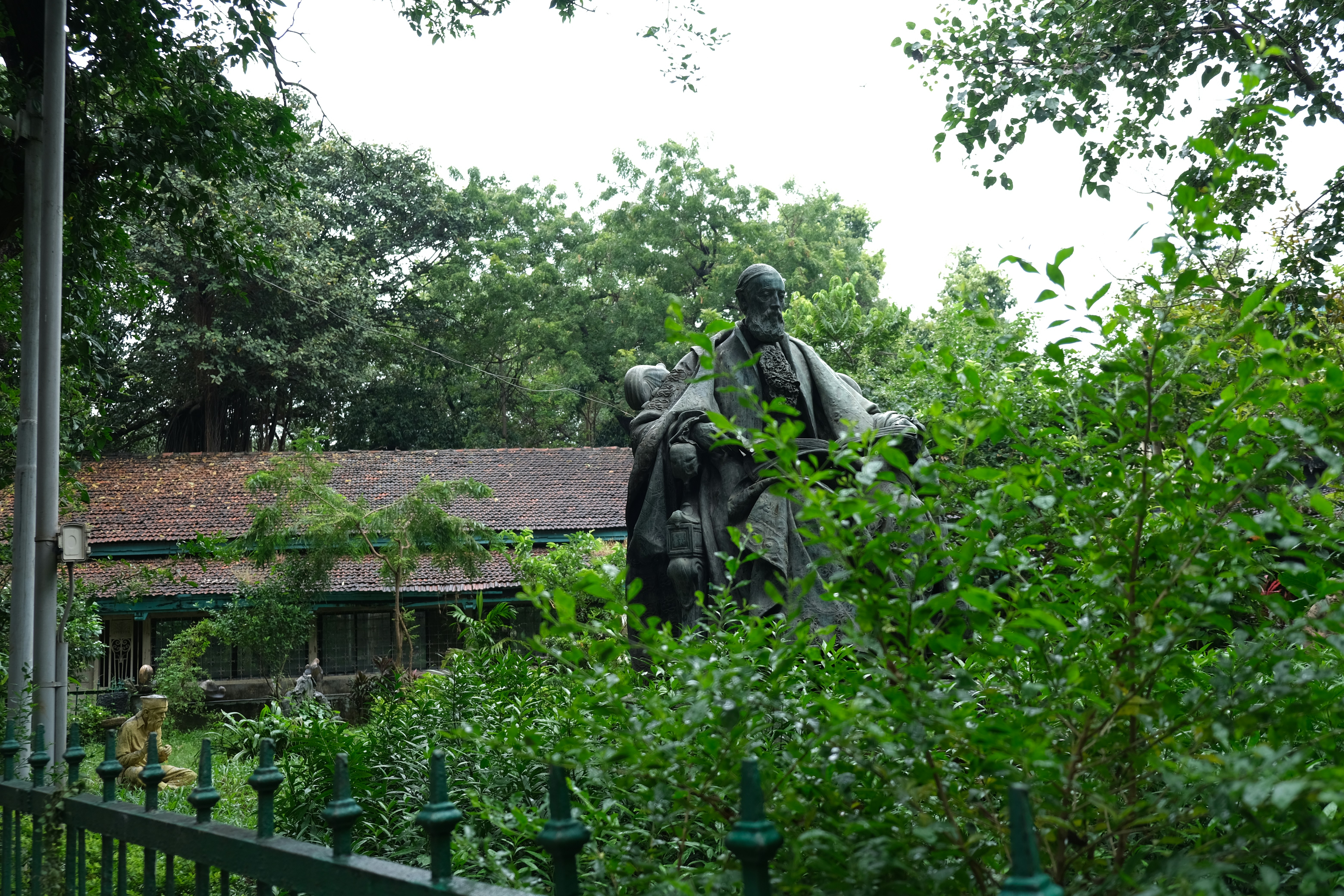 man in black coat statue near green trees during daytime, 