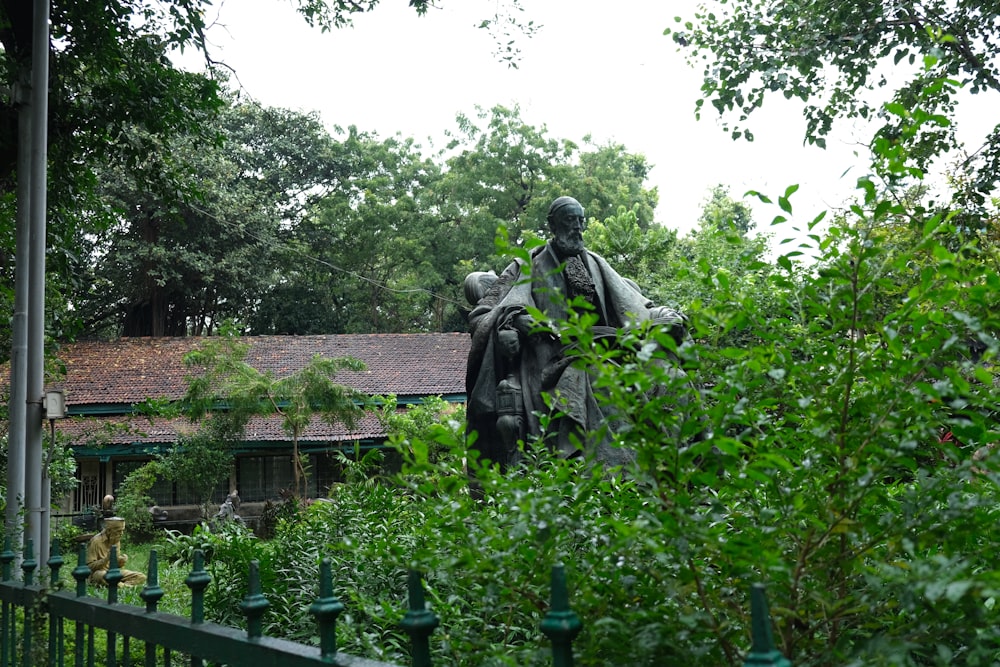 man in black coat statue near green trees during daytime