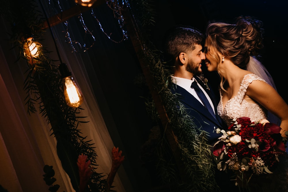 man in black suit kissing woman in white dress